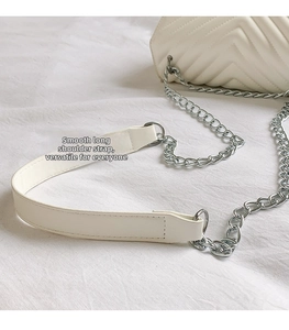 Détail de la bandoulière en chaîne argentée et cuir blanc sur sac matelassé chevron