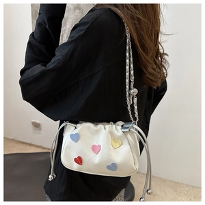 Détail du sac à bandoulière blanc avec patchs cœurs colorés et bandoulière en chaîne