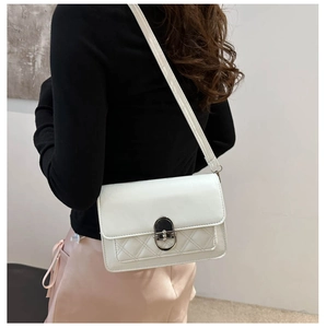 Gros plan d'un sac à bandoulière matelassé blanc avec fermoir argenté porté par un mannequin