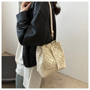 Side view of beige bucket bag with vintage 1981 print and leather strap on a model
