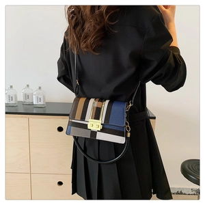 Detail of colorful striped crossbody bag with gold buckle on a minimalist background