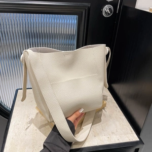 Chic beige lychee grain leather bucket bag with wide strap and minimalist front pocket