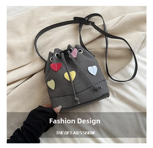 Dettaglio borsa a secchiello in twill grigio con toppe a cuore e chiusura a coulisse