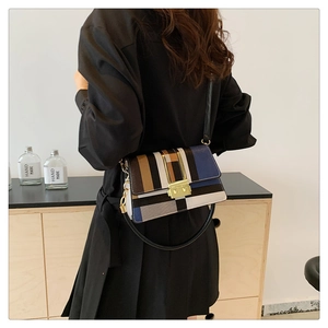 Detail view of a geometric striped small square bag with golden buckle and crossbody strap