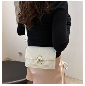 Detail van crème witte crossbodytas met ruitvormig stiksel en gouden ovale metalen sluiting