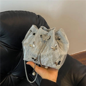 Silver metallic drawstring bucket bag with butterfly hardware and pearl charms
