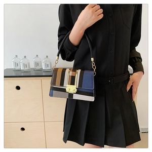 Detail view of geometric patchwork shoulder bag with gold clasp and leather handle