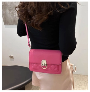 Detail van rozerode crossbodytas met klassieke gewatteerde stiksels en zilveren metalen slot