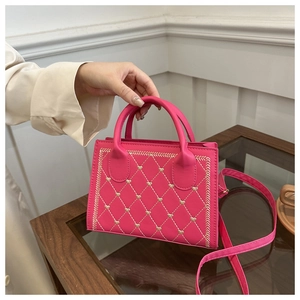 Detail of rose pink small square bag featuring heart-shaped diamond embroidery and handle