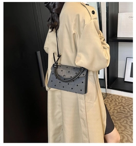 Detailansicht der grauen Polka-Dot Umhängetasche mit schwarzem Griff und Metallverschluss