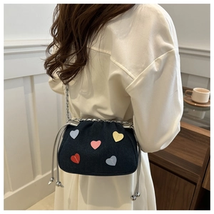 Detail of blue denim bucket bag with colorful heart patches and silver chain strap