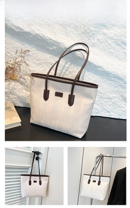 Detail of white textured tote bag with coffee-colored handles and branding plaque
