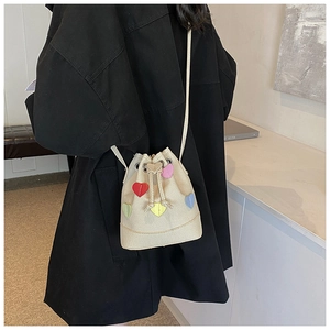 Dettaglio della borsa a secchiello in tela beige con cuori colorati e coulisse