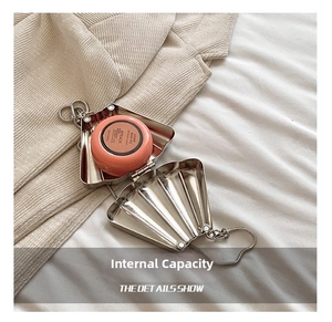 Macro view of silver shell-shaped metal clutch showing interior space for small cosmetics