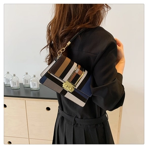 Detail of color-block flap bag with gold square clasp and leather chain strap on shoulder