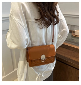 Brown leather crossbody bag with silver clasp and quilted detail on a model