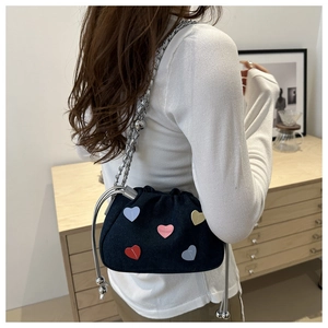 Detail of blue denim bucket bag with colorful heart patches and silver chain strap