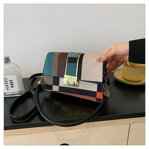 Detail of vintage patchwork shoulder bag with geometric blocks and gold lock on table
