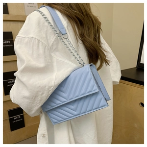 Détail du sac bandoulière bleu clair avec matelassage en V et chaîne en métal argenté