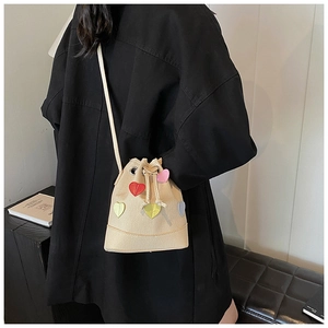 Vista dettagliata della borsa a secchiello in tela beige con cuori 3D colorati