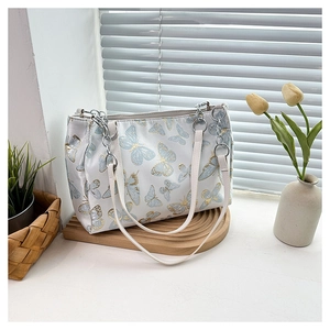 Detailed embroidery of butterfly patterns on a white satin shoulder bag with chain strap
