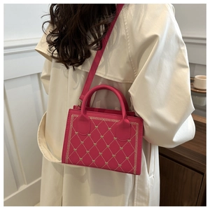 Detail of fuchsia quilted handbag with heart embroidery worn over a beige trench coat