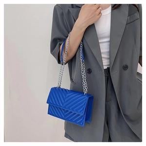 Détail du sac bandoulière bleu roi matelassé en V avec chaîne argentée sur un mannequin