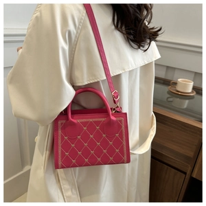 Detail of rose pink crossbody bag with gold heart quilting worn with beige trench coat