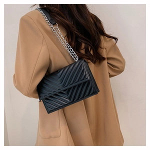 Détail du sac à bandoulière noir en cuir matelassé en V avec chaîne sur un modèle