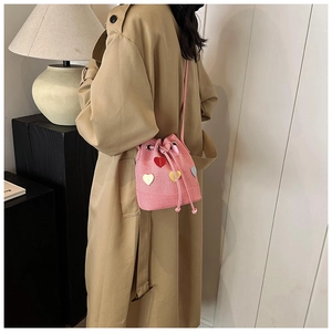 Dettaglio borsa a secchiello rosa con coulisse, toppe a cuore colorate e tracolla