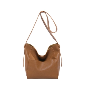 Brown pebbled leather bucket bag with adjustable shoulder strap and minimalist design