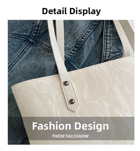 Détail du sac cabas blanc cassé montrant le cuir verni plissé et les rivets métalliques