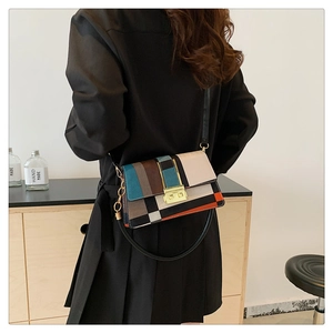 Detail of color-block crossbody bag with gold square clasp and chain strap on model