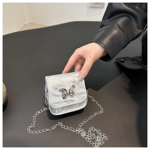 Close-up of mini silver chain bag with pleated texture and butterfly metal buckle