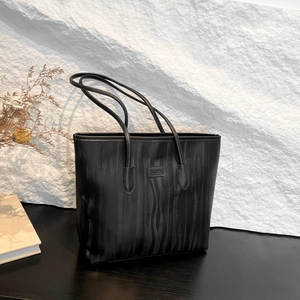 Minimalist black tote bag with vertical wavy texture and shoulder strap for daily commuting