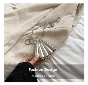 Close-up of a silver shell-shaped metal handbag with a glossy mirror finish and chain