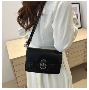 Detail of black faux leather bag with quilted rhombus pattern and silver oval twist lock
