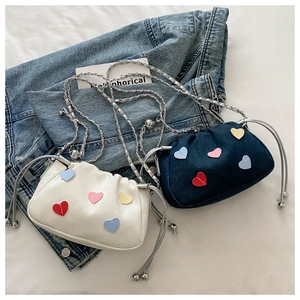 Détail de patchs cœur colorés sur mini sacs bandoulière en crème et denim avec chaînes
