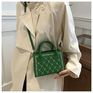 Green shoulder bag with diamond stitching and heart embroidery shown on a beige trench coat