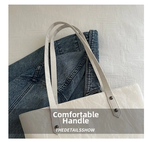 Détail du sac cabas blanc avec texture froissée et sangle rivetée sur tissu denim