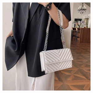 Détail d'un sac à bandoulière matelassé blanc avec une chaîne en argent élégante