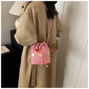 Borsa a secchiello rosa intrecciata con cuori colorati indossata da modella in trench