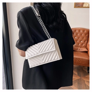 Gros plan d'un sac bandoulière blanc matelassé en chevron avec chaîne en argent
