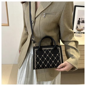 Detail of elegant black crossbody bag with quilted heart stitching and shoulder strap