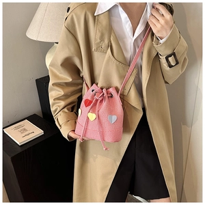 Dettaglio borsa a secchiello a righe rosa con toppe a cuore colorate e chiusura a coulisse