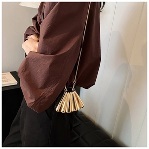 Detailed view of luxury gold fan-shaped metal evening bag with fine chain shoulder strap