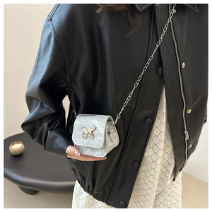 Detail of silver marble texture crossbody bag with butterfly clasp and chain strap