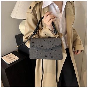 Close-up of grey star print handbag with knot handle and golden metal rings