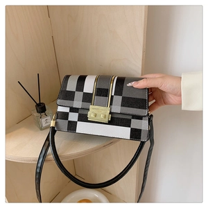Detail of crossbody bag with black and white color-block pattern and gold clasp