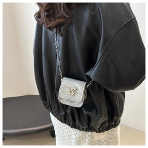Detail of silver marble saddle bag with metal butterfly and delicate chain strap